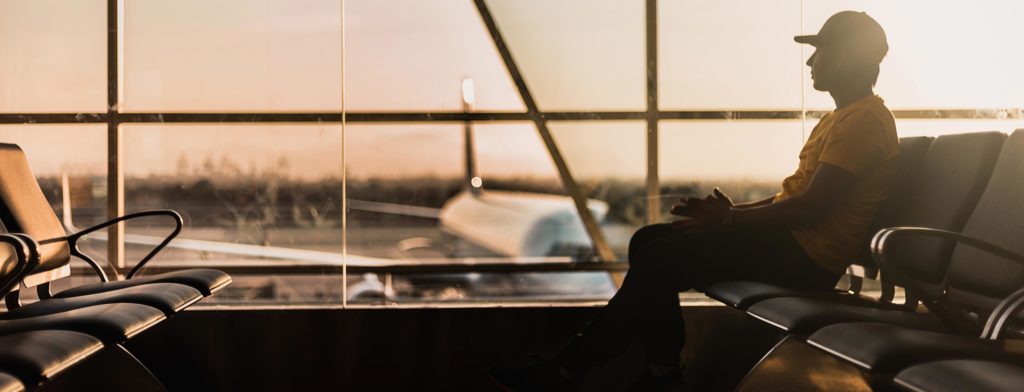 A man sitting at an airport, looking out at an aeroplane.