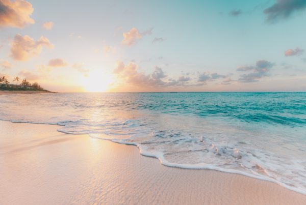 A close up image of the ocean lapping at a beach. The water is crystal blue.