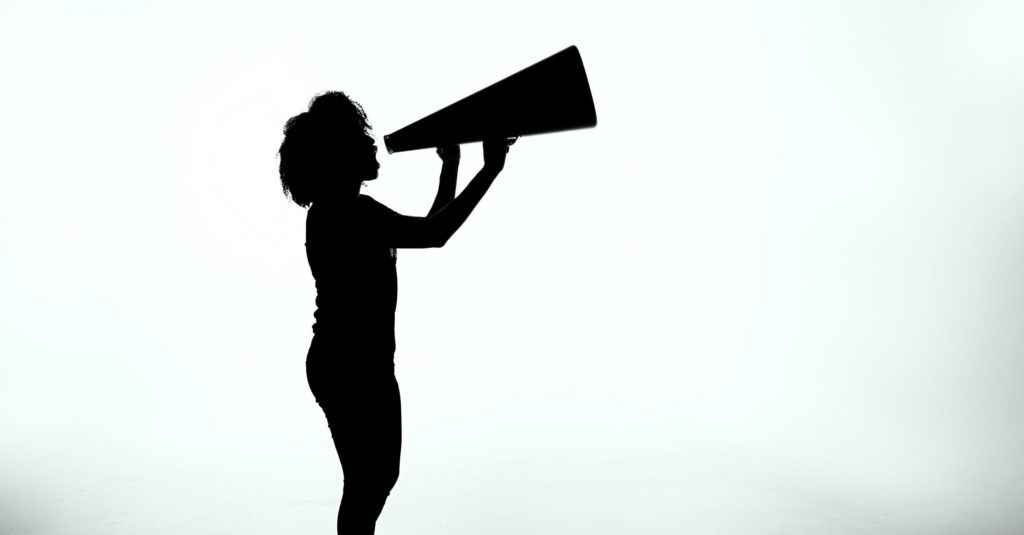 A silhouette of an individual speaking into a megaphone.
