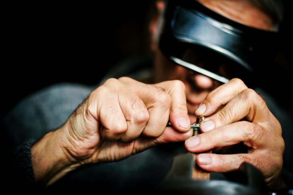 A man crafting a gold ring. He has some specialist headwear on for the process.