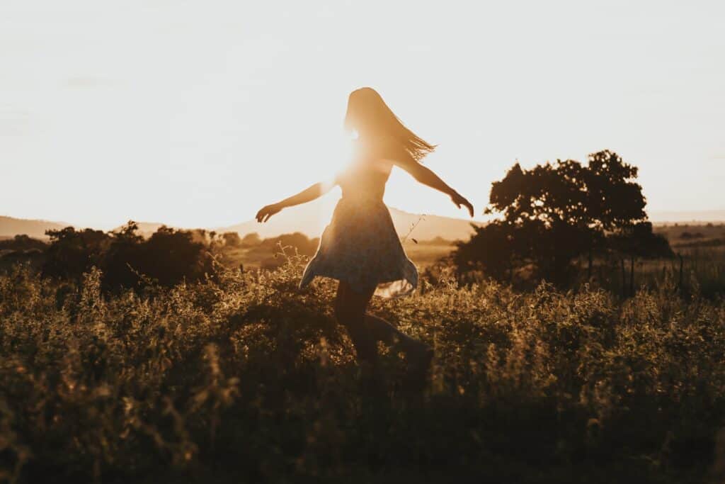Privacy Rights CF | Image is of a woman with long hair walkng through a open field at dusk. She is in silhouette so you cannot see her face. In the background there are tress and shrubs.